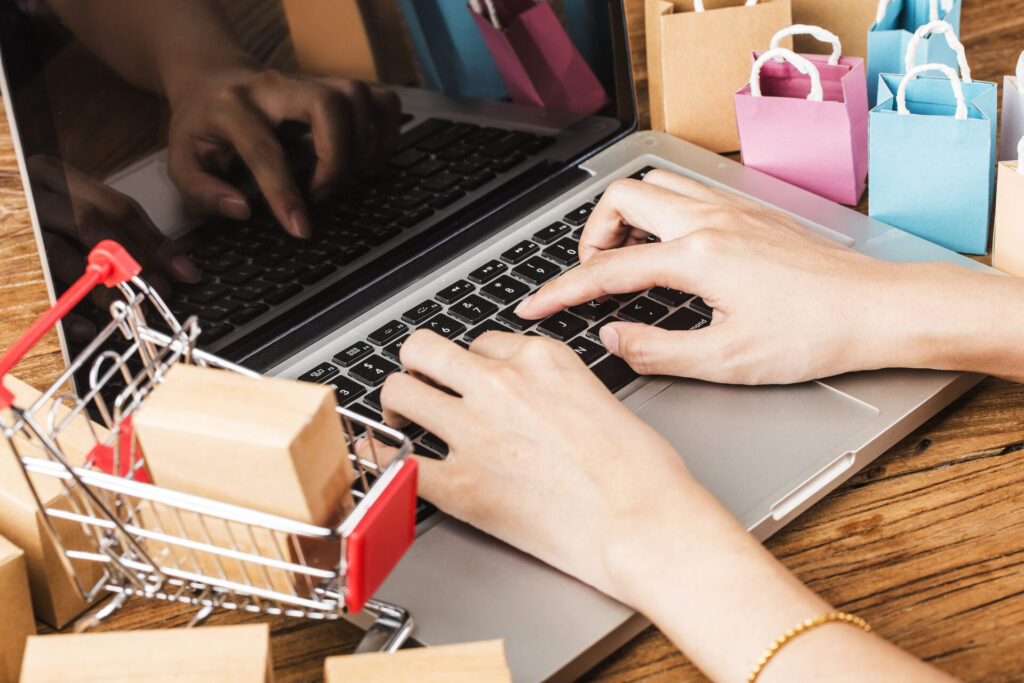 ネットショッピング中の手元とミニチュアの買い物カートと紙袋