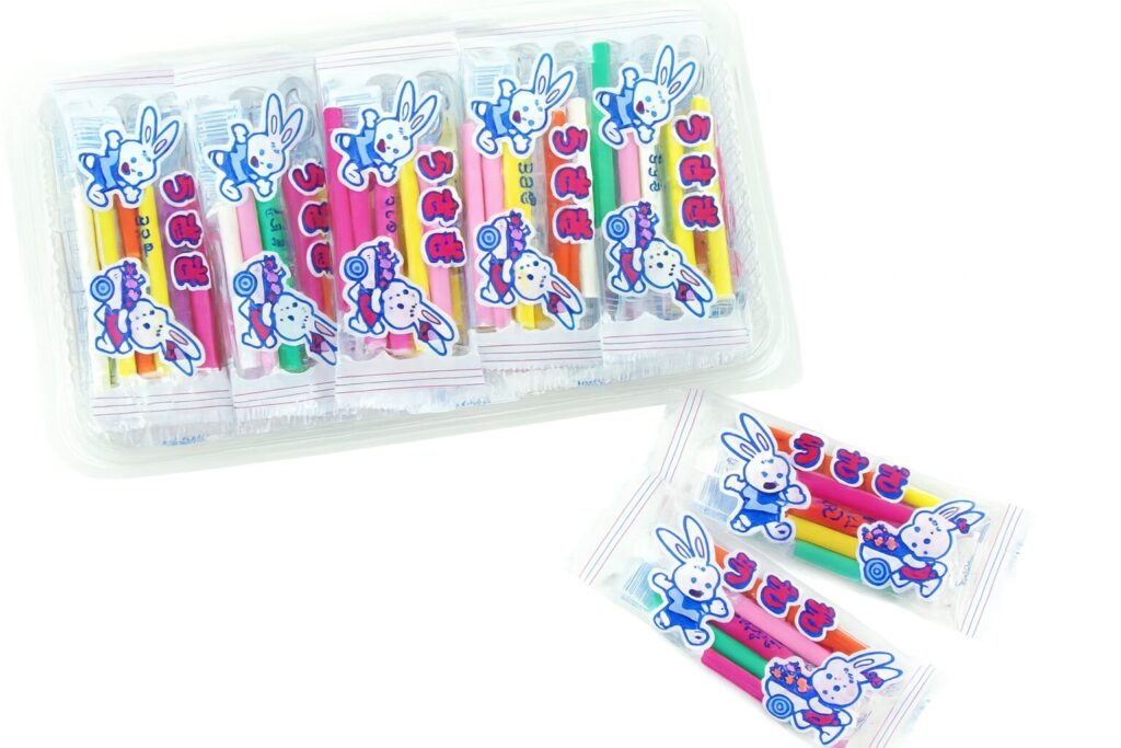 黄色、緑など、クレヨンのようにカラフルな「うさぎマンボ」がプラスチックケースにたくさん入っている様子。