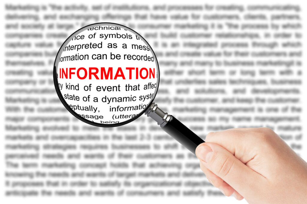英文テキストの上に虫眼鏡をかざし、「INFORMATION」という単語が拡大されている写真。データから重要ポイントを見つけ出す過程を表したイメージ。